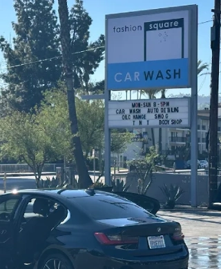 Car parked beside the Fashion Square Car Wash monument sign listing hours and services